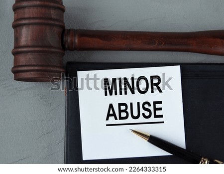 MINOR ABUSE - words on a white sheet with leather notebooks, a judge's hammer and a pen