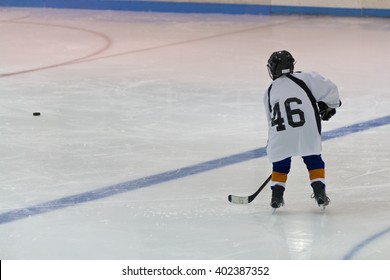 Minor Ice Hockey Child Skates With The Puck In An Arena During A Practice Drill