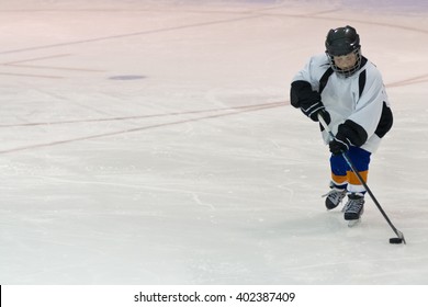 Minor Ice Hockey Kid Skates With The Puck In An Arena During A Game