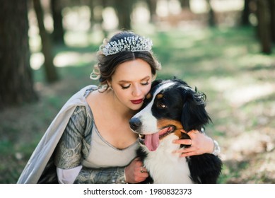 Minsk, Belarus - 04.14.2020. Young Glam Beautiful Lady Wearing Luxurious Gown And Coat Standing In A Woods With Her Dog.