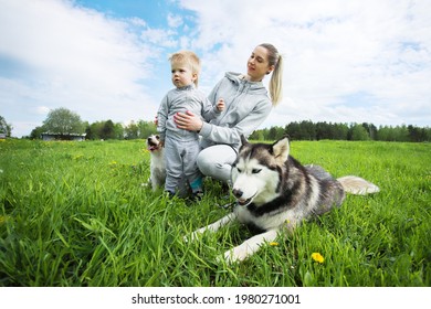 MINSK. BELARUS: 21.05.2021 - Child With Mom And Husky In Green Grass On The Background Of Blue Sky With Clouds. 