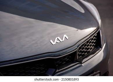 Minsk, Belarus. Apr 2022. KIA Motors new angular logo on hood of dark grey Kia Rio. Chrome KIA logo close up on dark grey hood, front grille detail 