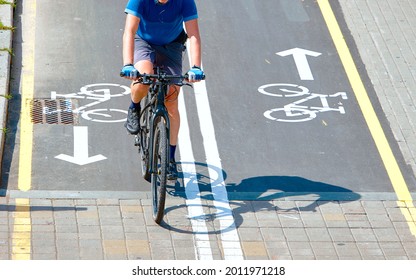 Minsk, Belarus. Aug 2019. Man Riding On Bicycle. Bike Path And Cyclist On Bicycle In City, View From Above. Bike Lane For Cyclist. Bicycle Road Sign Painted On Pavement. Bicycle Lane And Sign On Road