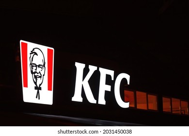 Minsk, Belarus. Aug 2021. KFC restaurant glowing sign at night. KFC signboard on facade wall of building at night. Kentucky Fried Chicken restaurant sign, fast food chain, Colonel Sanders logo