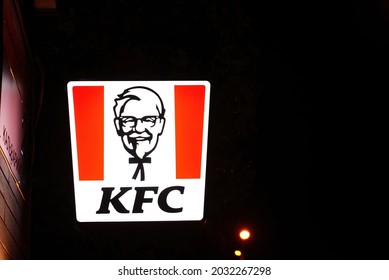 Minsk, Belarus. Aug 2021. KFC restaurant glowing sign at night. KFC signboard on facade wall of building at night. Kentucky Fried Chicken restaurant sign, fast food chain, Colonel Sanders logo.