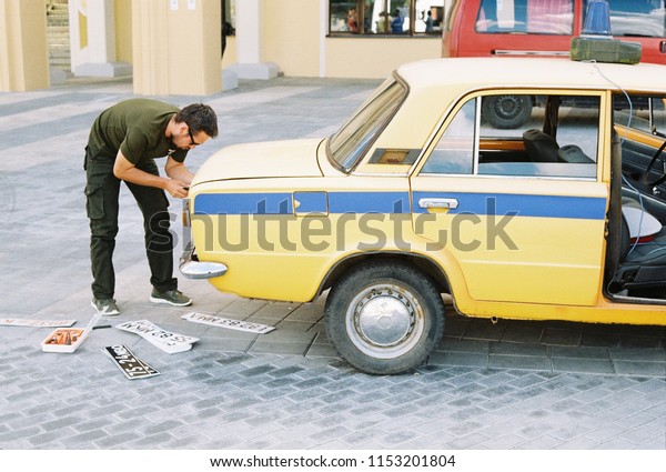 Minsk, Belarus - August 08, 2018:\
Movie making process - changing car plates to look really according\
to time at which the action of the film takes\
place\
