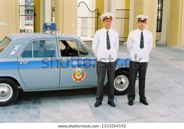Minsk, Belarus - August 08, 2018: Movie\
making process - shooting a movie about the Olympic Games in Moscow\
in 1980 - two policemen standing by a police\
car\
