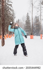 Minsk, Belarus - December 03, 2020: Winter Fun Games In The Snowy Mountains - Woman Throws Snowballs - Warm Winter Suit