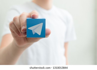 Minsk, Belarus. February, 2019. Teenager Boy Holds Social Network Telegram Logo In His Hand. White Background.