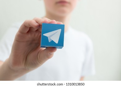 Minsk, Belarus. February, 2019. Teenager Boy Holds Social Network Telegram Logo In His Hand. White Background.