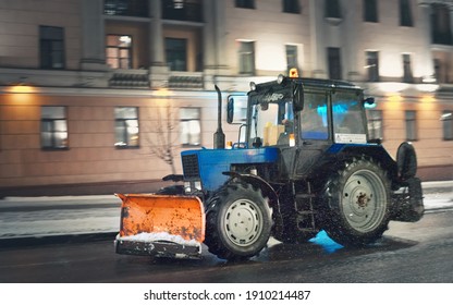 Minsk, Belarus. Jan 2021. Motion Blur Tractor With Snow Plow Riding On Night Road. Road Maintenance At Winter Season. Cleaning Road At Night. Heavy Machinery Working On City Street During Snow Storm