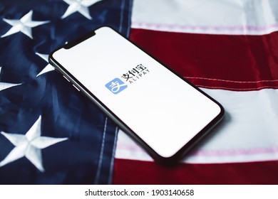 Minsk, Belarus - Jan 27, 2021: AliPay logo on the phone display with USA (American) flag. AliPay is a mobile payment app.