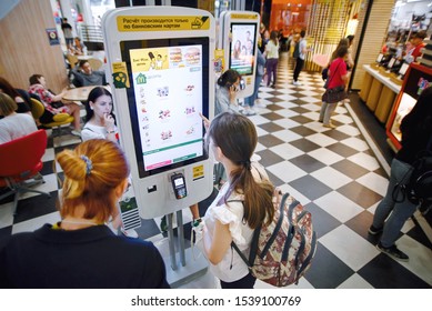 Minsk, Belarus. Jun 2019. People use self service screens at McDonald's restaurant. Hungry customers place orders and pay through self-ordering kiosk / terminal. Fast food restaurant chain.