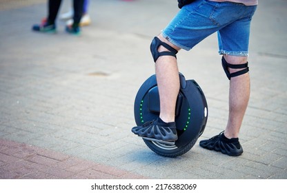 Minsk, Belarus. Jun 2022. Man With Knee Pads On Electric Unicycle (EUC), Stand On Pedestrian Crossing. Driving Around City Streets On Electric Monowheel. Man Travel On Mono Wheel.