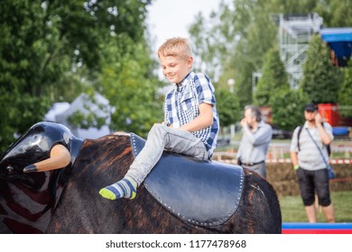 MINSK, BELARUS - MAY 1, 2017: A child enjoys the adrenaline rush while securely strapped a mechanical bull amusement ride