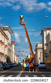 Minsk, Belarus. May 2018. Electrician In Lift Bucket Repair Damaged Wire At Height. Man Repair Broken Wire On Truck Crane. Worker In Lift Bucket, Electrician Service Team Repair Power Line, Men Work