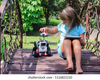 Minsk, Belarus - May, 2018: Little Girl Programs Lego Robot Mindstorms EV3 On IPad Apple In Summer Stem Robotic Camp. Elementary School In The Garden. Robotic Class. Lesson. AI. Code Bot.