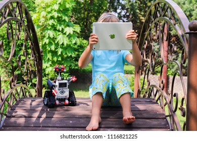 Minsk, Belarus - May, 2018: Little Girl Programs Lego Robot Mindstorms EV3 On IPad Apple In Summer Stem Robotic Camp. Elementary School In The Garden. Robotic Class. Lesson. AI. Code Bot.