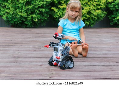 Minsk, Belarus - May, 2018: Little Girl Programs Lego Robot Mindstorms EV3 On IPad Apple In Summer Stem Robotic Camp. Elementary School In The Garden. Robotic Class. Lesson. AI. Code Bot.