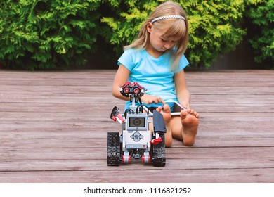 Minsk, Belarus - May, 2018: Little Girl Programs Lego Robot Mindstorms EV3 On IPad Apple In Summer Stem Robotic Camp. Elementary School In The Garden. Robotic Class. Lesson. AI. Code Bot.