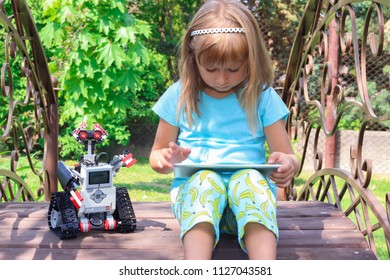 Minsk, Belarus - May, 2018: Little Girl Programs Lego Robot Mindstorms EV3 On IPad Apple In Summer Stem Robotic Camp. Elementary School In The Garden. Robotic Class. Lesson. AI. Code Bot.