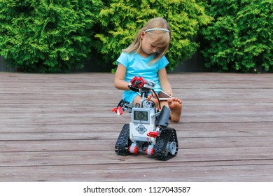 Minsk, Belarus - May, 2018: Little Girl Programs Lego Robot Mindstorms EV3 On IPad Apple In Summer Stem Robotic Camp. Elementary School In The Garden. Robotic Class. Lesson. AI. Code Bot.