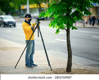 Minsk, Belarus. May 2020. Photographer Using Professional Digital Camera Nikon On Tripod Outdoor. Work During Quarantine, Man Shooting City Timelapse. Journalist Shoot People On Crowded Street 