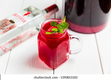 Minsk, Belarus, May 24, 2018. A cold refreshing cherry alcoholic cocktail in a glass jar with Beefeater London Dry Gin, ice and mint. 