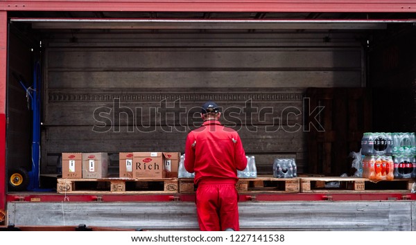 Minsk, Belarus - Nov 2018. Lorry with boxes of\
Coca-cola, water and juice. Delivery worker checks an order. food\
delivery to a restaurant, pub,\
cafe