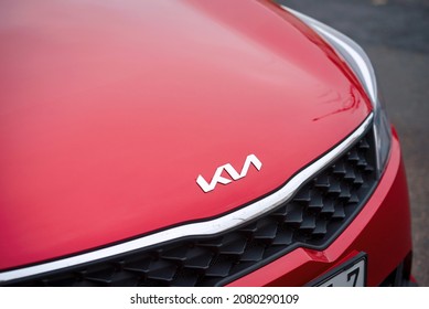 Minsk, Belarus. Nov 2021. KIA Motors new angular logo on red hood of red Kia Rio. Chrome KIA logo close up on red hood, front grille detail 