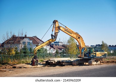 Minsk, Belarus. Ocr 2021. Hyundai 330 LC-95, Crawler excavator mounted vibratory hammer. Heavy duty vehicle with vibro hammer. Rolled metal H-beam lay on the ground