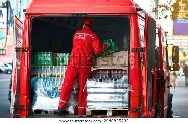 Minsk, Belarus. Sep 2021. Delivery driver unload car\
with boxes of beverage, restaurant delivery. Van with Coca-cola\
drinks. Worker delivering beverages of Coca-Cola company, Coca Cola\
delivery man
