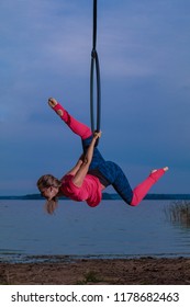 MINSK, REPUBLIC OF BELARUS - SEPTEMBER 3, 2018: Field training aerial gymnastics. Girls perform acrobatic on the ring on the lake. 

For these photos a neutral density filter and an external flash.