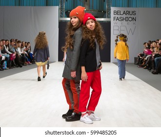 MINSK/BELARUS - NOVEMBER 2016: Unknown kids fashion models stands on runway at Belarus Fashion Week on November 6, 2016 in Minsk, Belarus. Two girls in warm clothes and red hats standing on podium
