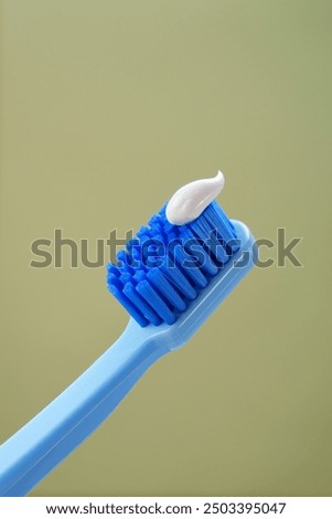 Mint background. Blue toothbrush with toothpaste on a green background, close-up. 