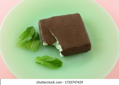 Mint Chocolate Chip Ice Cream Bar Covered In Milk Chocolate On Green Plate With Fresh Mint Leaves On Pink Background