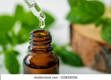 mint essential oil drop falling from dropper into the bottle