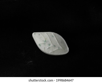 A Mint Leaf Shaped White Mint Candy With Refreshing Blue Microgranules On Isolated Black Background. Delicious Confectionery. Cooling Menthol For Sore Throat. A Leaf Shaped Menthol Candy On Black.