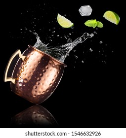 Mint, Lime And Ice Cube Falling Into A Splashing Moscow Mule Isolated On Black