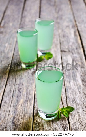 Mint liqueur in a glass on a wooden surface. Selective focus.