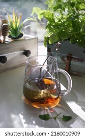 Mint In A Pot On A Table In The Sun Next To A Jar Of Honey And A Cup Of Tea