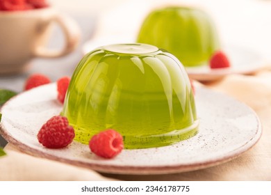 Mint and raspberry green jelly on gray concrete background and orange linen textile. side view, close up, selective focus.