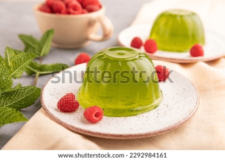 Mint and raspberry green jelly on gray concrete background and orange linen textile. side view, close up, selective focus.