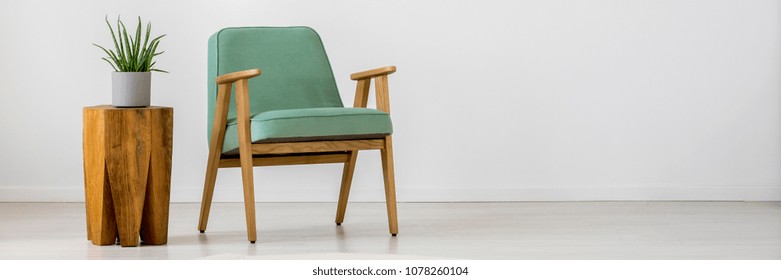 Mint retro armchair and plant on wooden, small table in simple living room interior - Powered by Shutterstock