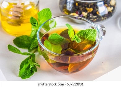 Mint tea in a cup, a jar of honey, a cookie in a jar, on a white tray in bed