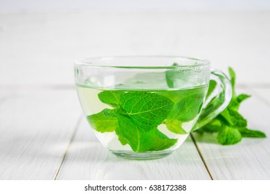 Mint tea in a cup on a white wooden table