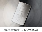 Minted silver bar weighing 500 grams on an abstract metal background.