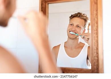 Minty Fresh Breath Is The Way To Start The Day. Shot Of A Young Man Brushing His Teeth At Home.