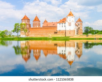 Mir, Belarus. Castle Complex Mir reflected in lake On Sunny Day with blue sky Background. Old medieval Towers and walls of traditional fort from unesco world heritage list