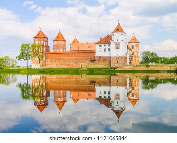Mir, Belarus. Castle Complex Mir reflected in lake On Sunny Day with blue sky Background. Old medieval Towers and walls of traditional fort from unesco world heritage list